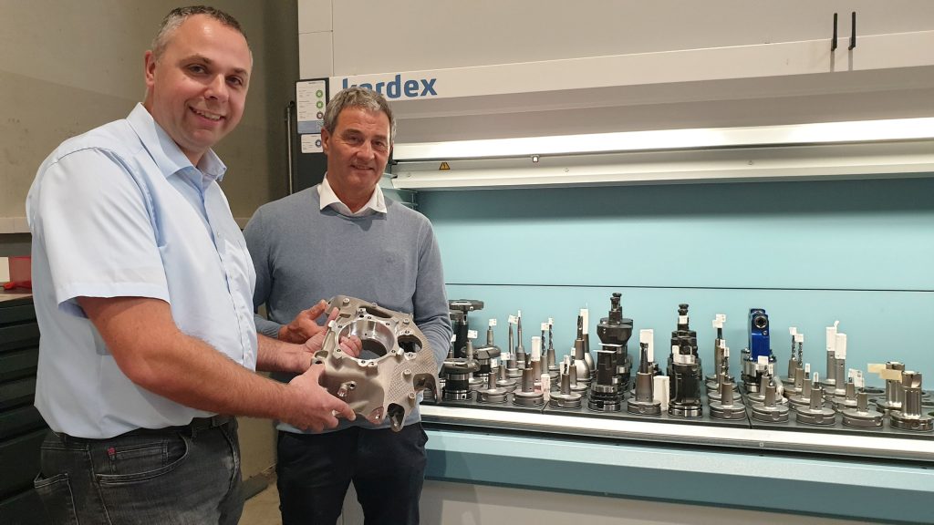 Helmut Häckl, VD för Schabmüller (höger) och Stephan Streck, teknisk konsult på MAPAL, med ett hjullagerhus. Verktygen som används för tillverkningen syns i bakgrunden.